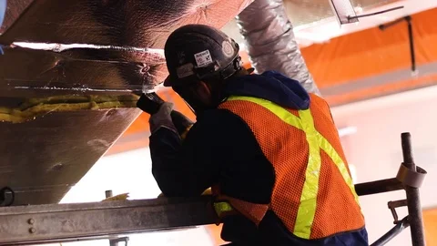 Construction worker cutting air vent,  wearing construction hat and vest Stock Footage 87346638