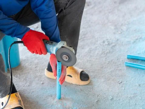 A construction Worker Cutting Blue PVC Pipe with Electric Angle. Stock Photos