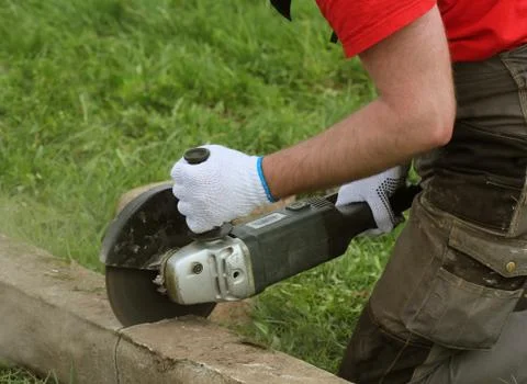 Construction worker cutting concrete plate for fence foundation using a cut-o Stock Photos