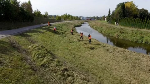 Construction worker cutting grass on a small river Stock Footage 105198414