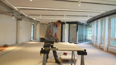 Construction worker cutting large panel with utility knife on workbench inside Stock Footage 331306088