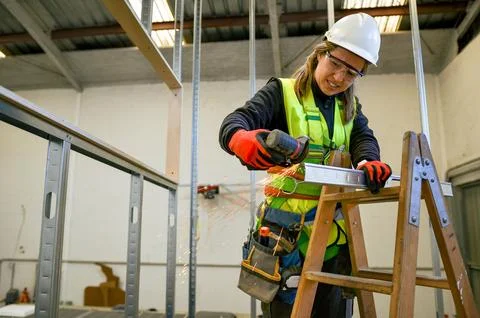 Construction worker cutting metal profile for plasterboard mounting using a.. Stock Photos
