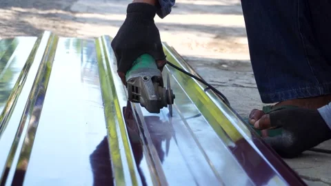 Construction worker cutting metal roofing sheet with angle grinder Stock Footage 340543388