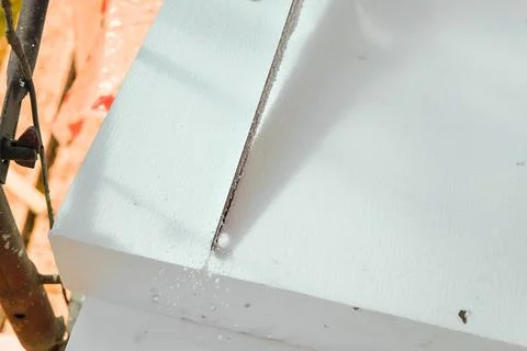 Construction worker cutting polystyrene foam heat insulation with hand saw,.. Stock Photos