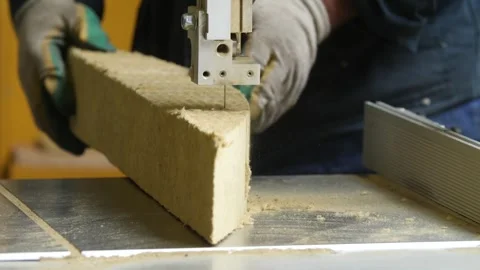 Construction worker cutting rock wool insulation panel with bandsaw. Stock Footage 313815312