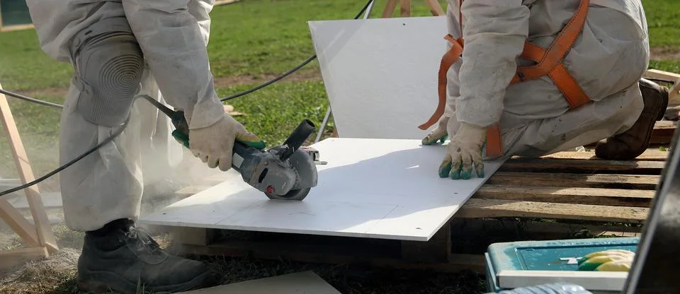 Construction Worker Cutting White Panel With Grinder on a Sunny Day Stock Photos