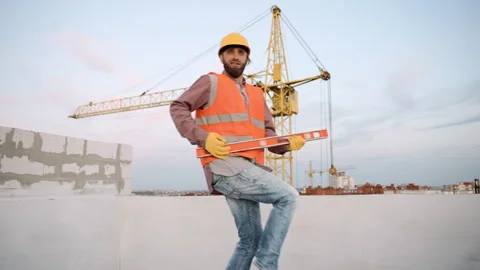 Construction worker dance at a site measures levels with a tool during sunset Video stock 286052221