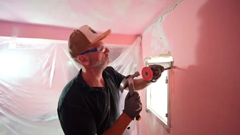 Construction worker demolishing a pink wall around a window frame Видео 347640665