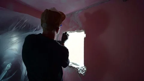 Construction worker demolishing a plaster wall with a hammer 库存影片 347640617