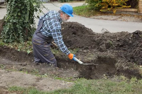 Construction worker digging trench using shovel Stock Photos