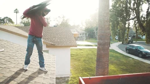 Construction Worker Disposing Roofing Shingles from Residential Roof Stock Footage 329269463