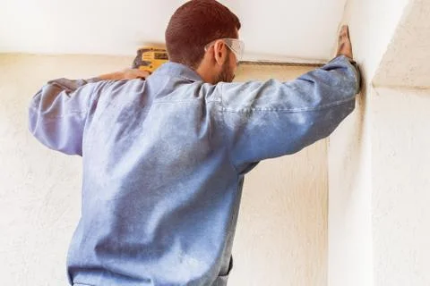 Construction worker with drill perforator making hole in the wall Stock Photos