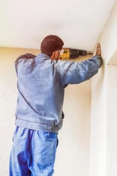 Construction worker with drill perforator making hole in the wall Stock Photos