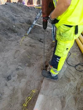Construction worker drilling during summer infrastructure project Stock Photos