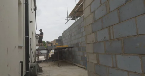 Construction worker drilling a hole into a wall while working on a building site Stock Footage 246379971