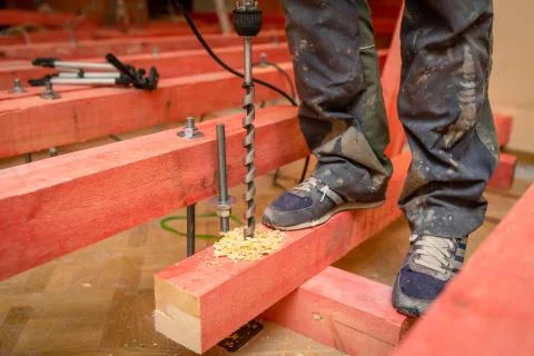 Construction worker drilling  wooden blocks by perforator with long bore bit Stock Photos