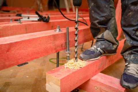 Construction worker drilling  wooden blocks by perforator with long bore bit Stock Photos