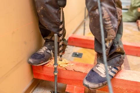 Construction worker drilling  wooden blocks by perforator with long bore bit Stock Photos