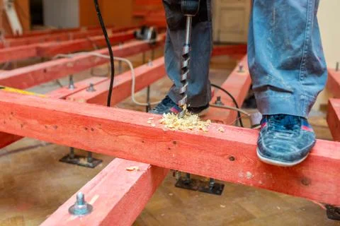 Construction worker drilling  wooden blocks by perforator with long bore bit Stock Photos