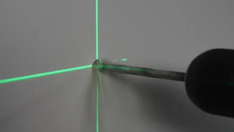 Construction worker drills a hole in wall for a dowel by using laser level Stock Footage 305433906