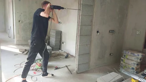 Construction worker drills wall in new building under renovation in urban area Stock Footage 325312780