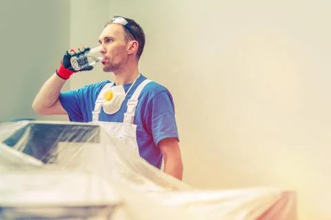 Construction Worker Drinking Water. Work Break. Office Interior Painting. Stock Photos