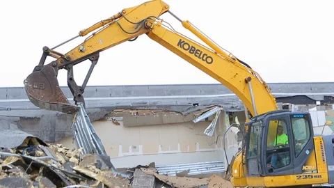 Construction worker drives controls heavy equipment at demolition site A Stock Footage 125055456