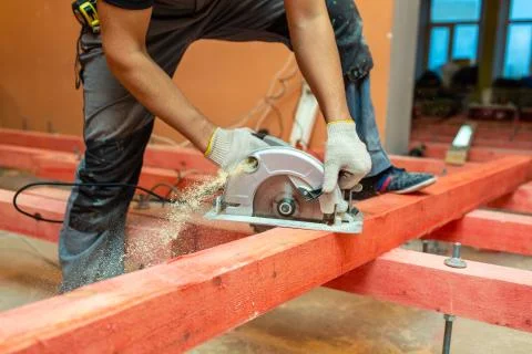 Construction worker with electrical circular saw saws wooden block and a lot of Stock Photos