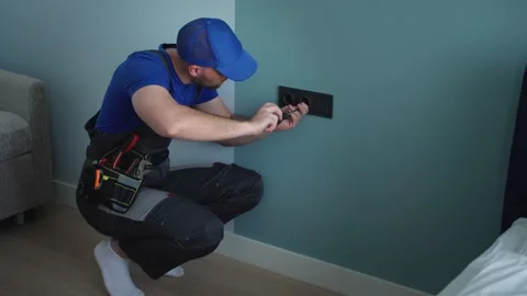 Construction worker electrician assembles an electrical outlet in an apartment Stock Footage 252660496