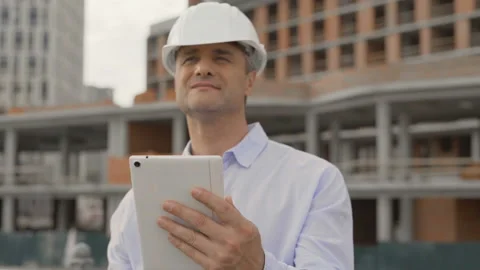 Construction worker, engineer architect using tablet walking on work site. Chief Stockbeeldmateriaal 111765009