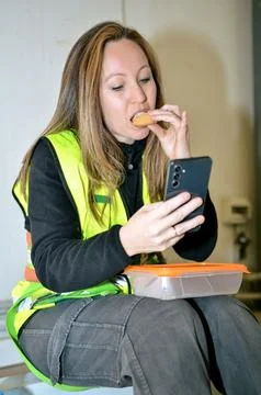 Construction worker enjoying lunch break with smartphone and snack Stock Photos