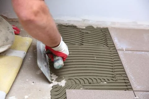 The construction worker evenly spreads the surface of the stairs with cement adh Foto stock