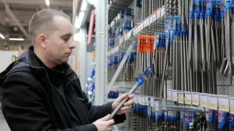 Construction worker examining drill bits at hardware store, comparing sizes and Foto stock