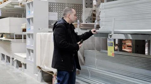 Construction worker examining metal profiles, comparing specifications on Stock Photos