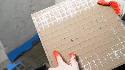 Construction worker examining tile before installation. Stock Photos