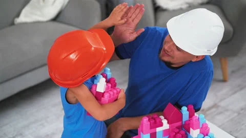 Construction worker father with his son wearing construction helmets playing Stock Footage 131780981