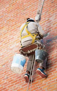 Construction Worker fixing a brick wall hang up with rappel chair's Stock Photos