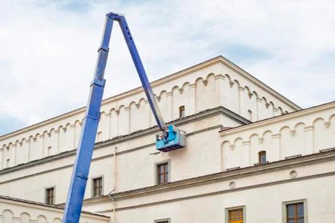 Construction worker fixing house facade using lifting boom machinery Stock Photos