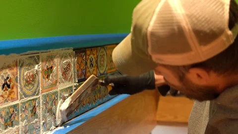 Construction worker focusses on applying grout to a row of ceramic tiles. Stock Footage 101434738