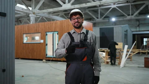 Construction worker gesturing thumbs up in modular house factory Stock Footage 313089840