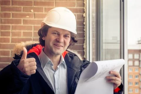A construction worker giving his thumbs-up in front of a newly constructed Stock Photos