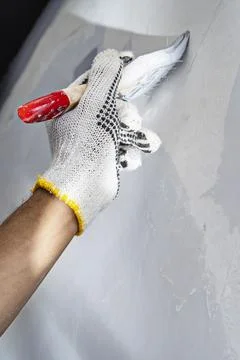 Construction worker in gloves using a paintbrush to apply paint to a wall d.. Stock Photos