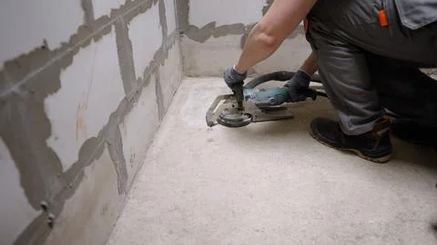 Construction worker grinding concrete surface with power tool Stock Photos