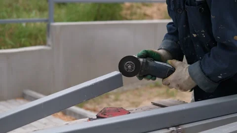 Construction worker grinding gray metal railing outdoors with handheld angle Stock-Footage 344878344