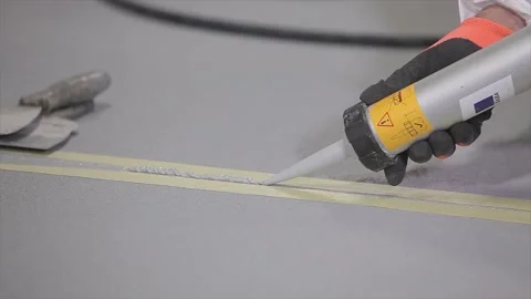 Construction worker grouting seams in concrete floor. The builder covers the Vidéo 218451165