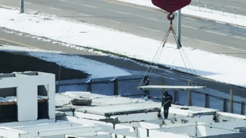 Construction worker guiding precast concrete slab carefully lifted and Stock Footage 323913173