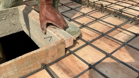 Construction worker hammering a nail into wooden formwork for a concrete slab Видео 334533853
