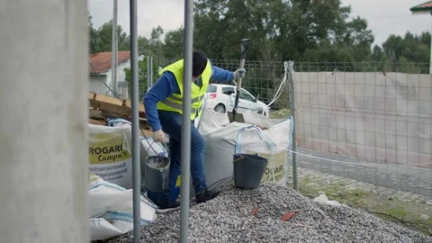 Construction Worker Handling Bucket of Sand in Slow Motion at a Job Site Vidéo 299771827