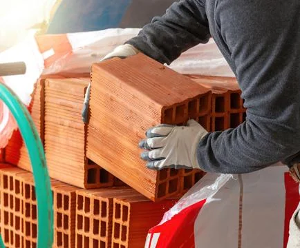 Construction worker handling hollow bricks on a building site Foto stock