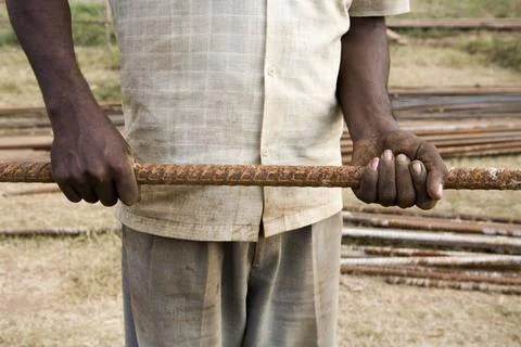 A construction worker handling iron roads with his bear hands ; Ahmedabad ... Photos